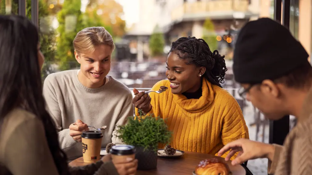 tre unga människor sitter på ett café