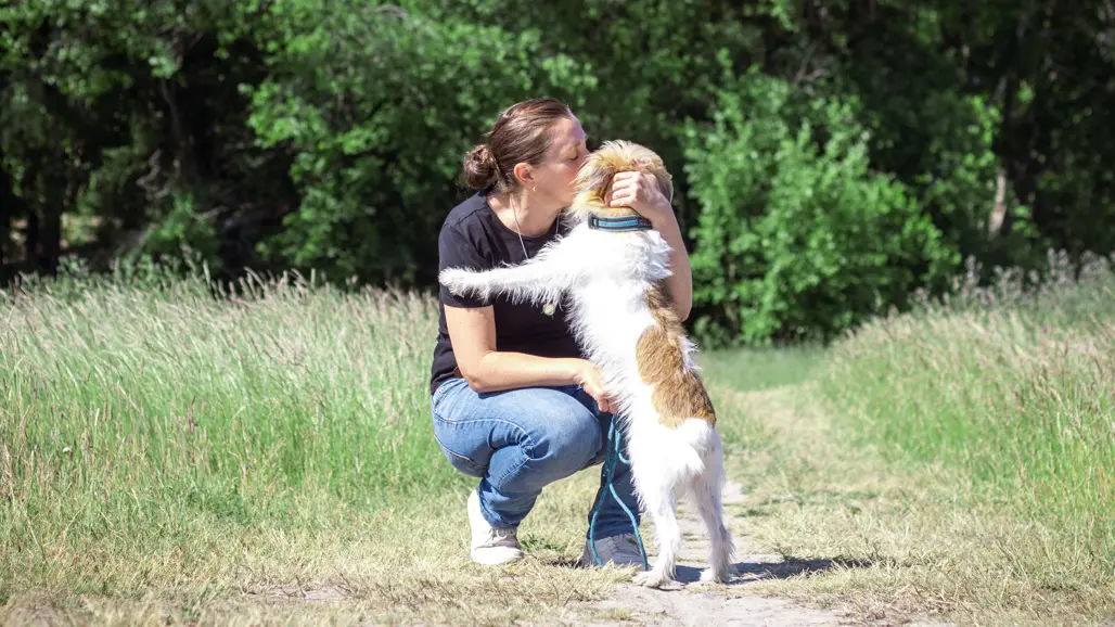 En kvinna gosar med en hund på en gångstig. Foto.