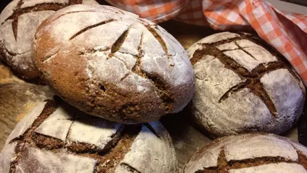 Mörka runda bröd i en korg med röt-vit duk.