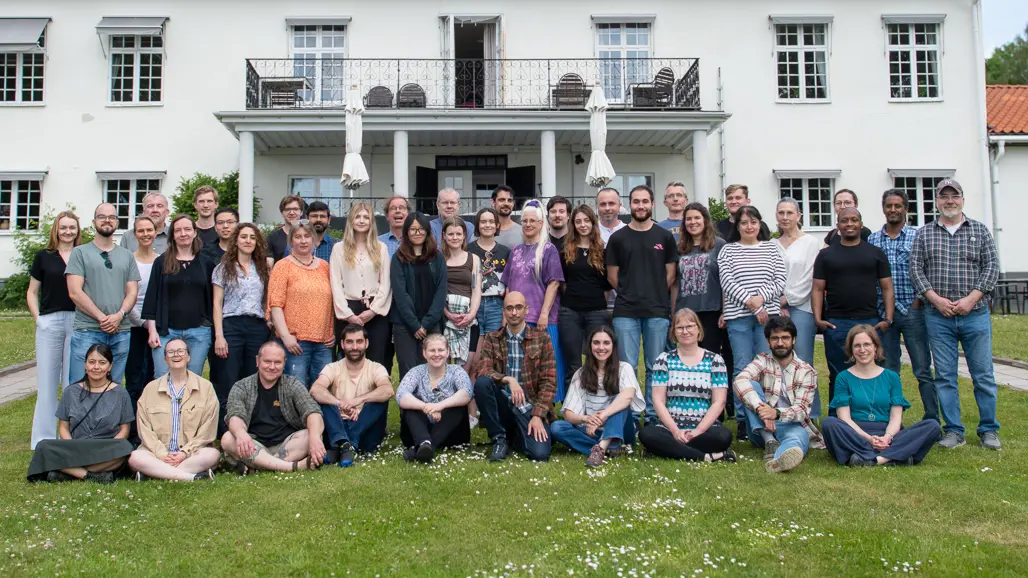 Group photo of many persons outside a white building.