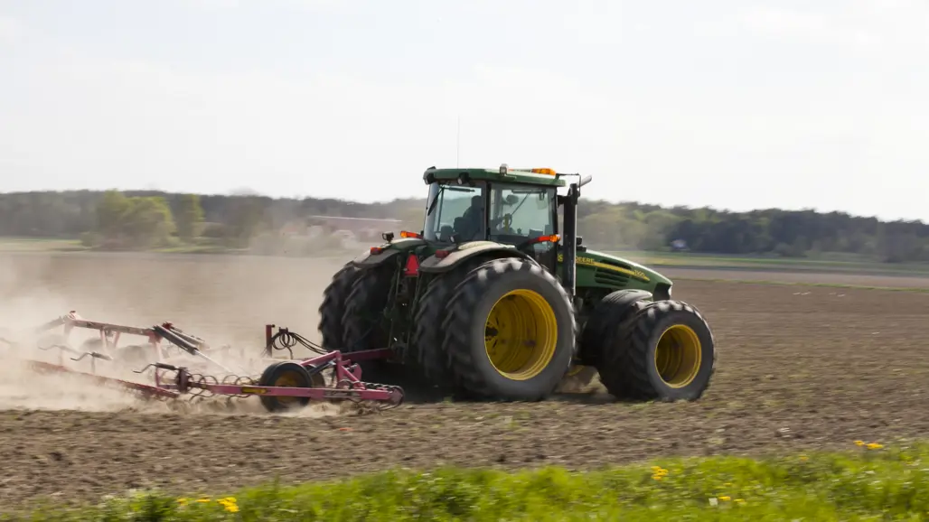 36 / 5 000 A tractor with a harrow drives in a field.
