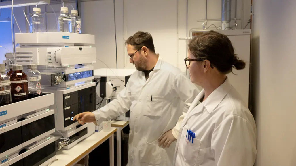 Två personer vid ett analysinstriument. Foto.