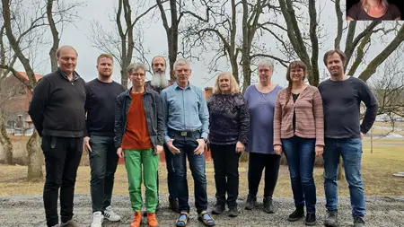 9 människor på rad i en gräsbacke. Foto