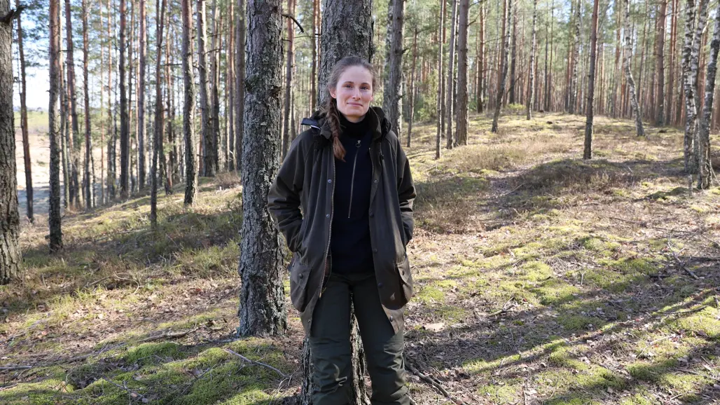 kvinna står lutad mot ett träd i skogen