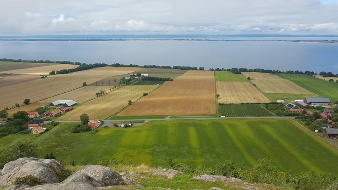 A landscape with fields and water in the background.