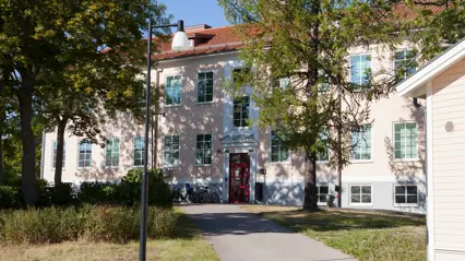 Kustlaboratoriets byggnad i Öregrund. En byggnad med ljusrosa fasad fotograferad en solig sommardag.